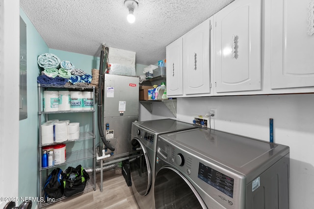 laundry room featuring cabinets, separate washer and dryer, a textured ceiling, electric panel, and light hardwood / wood-style floors