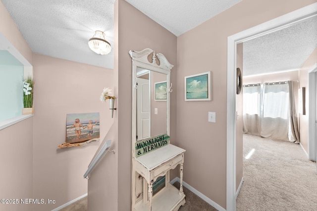 hallway with carpet flooring and a textured ceiling