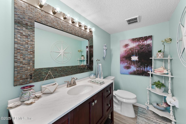 bathroom featuring vanity, hardwood / wood-style floors, a textured ceiling, and toilet