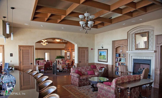 living room featuring coffered ceiling, a notable chandelier, dark hardwood / wood-style flooring, and a fireplace