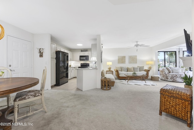 kitchen featuring ceiling fan, white cabinets, light colored carpet, and black appliances