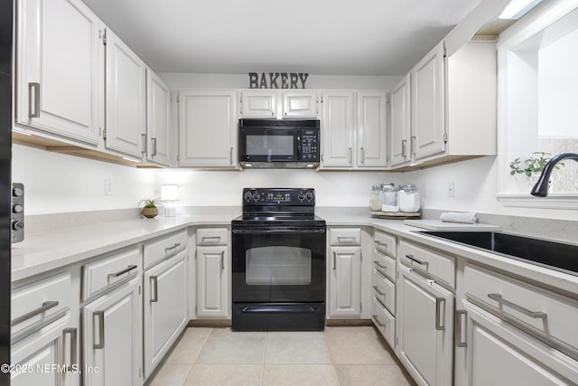 kitchen featuring sink, light tile patterned floors, white cabinets, and black appliances