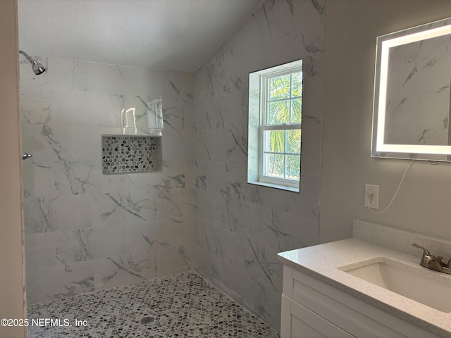 bathroom featuring tiled shower, vanity, and lofted ceiling