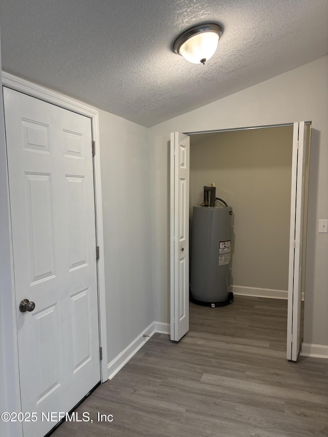 interior space with hardwood / wood-style flooring, lofted ceiling, electric water heater, and a textured ceiling