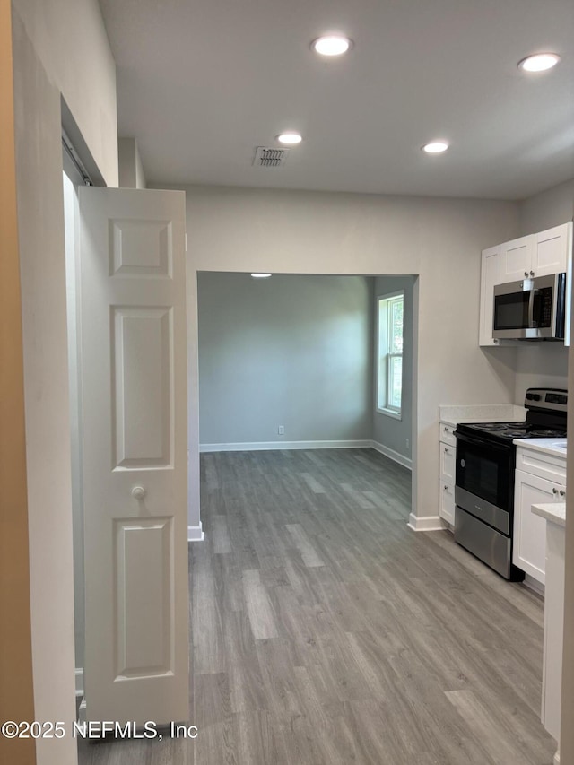 kitchen featuring white cabinetry, stainless steel appliances, and light wood-type flooring