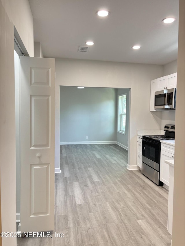 kitchen with light hardwood / wood-style floors, white cabinets, and appliances with stainless steel finishes