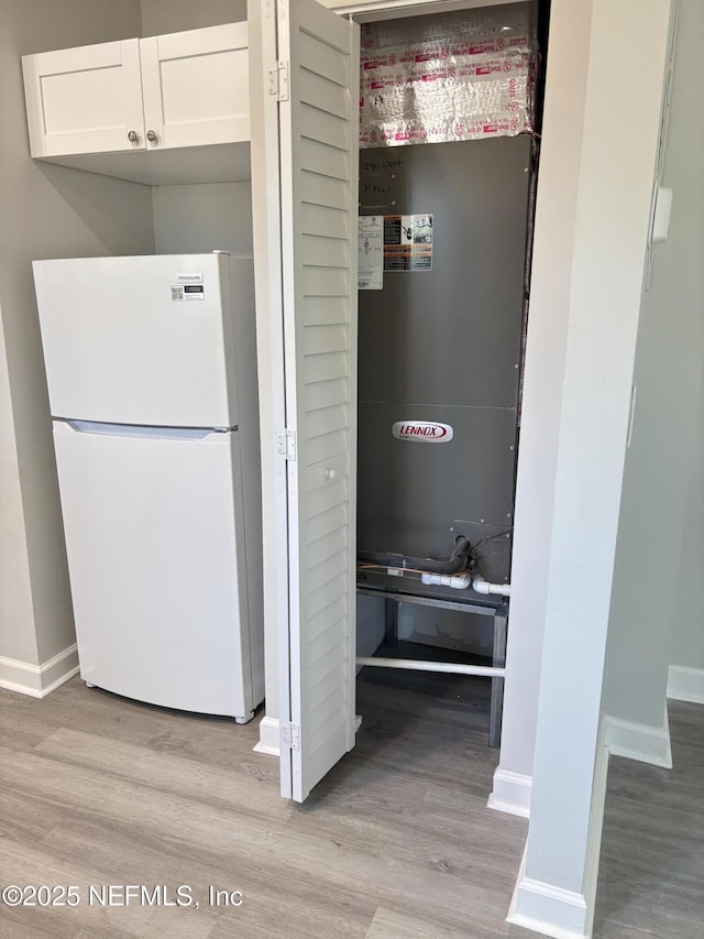 interior space featuring white refrigerator, white cabinetry, and light hardwood / wood-style floors