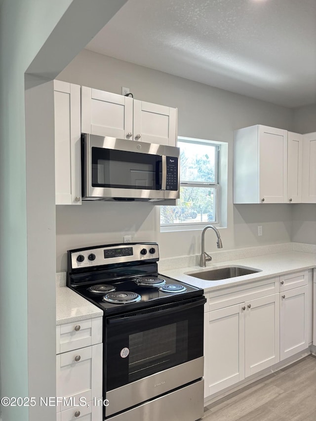 kitchen with white cabinetry, sink, and electric range oven