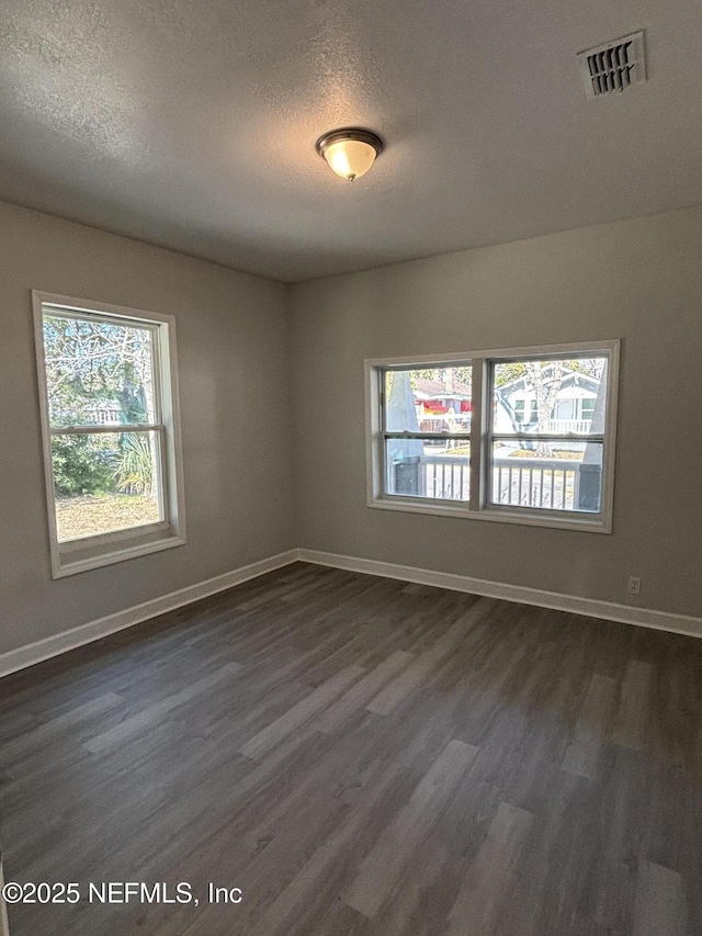 empty room featuring a textured ceiling and dark hardwood / wood-style flooring