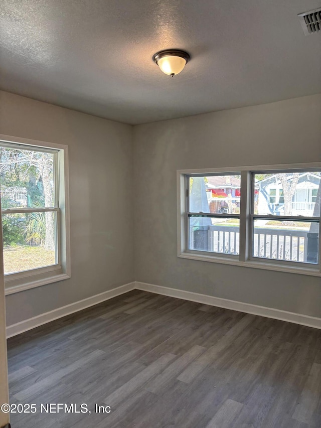 spare room featuring dark hardwood / wood-style flooring and a textured ceiling