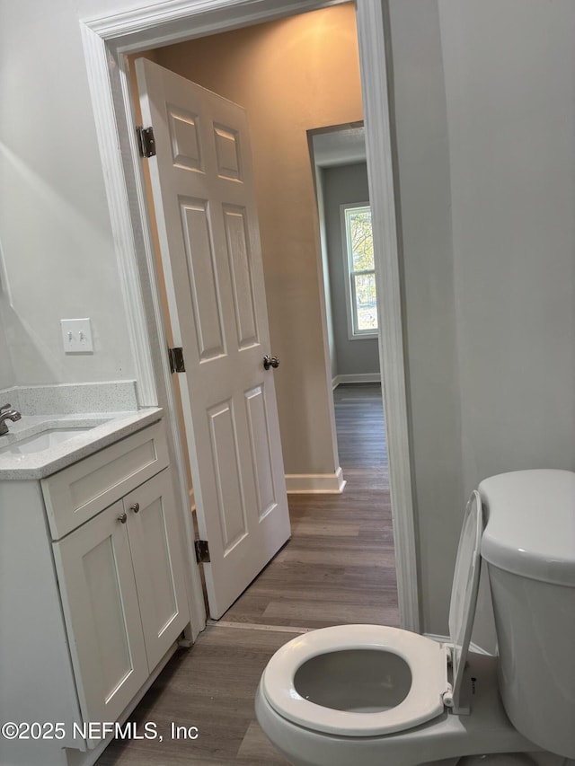 bathroom with vanity, toilet, and hardwood / wood-style floors