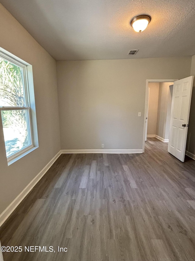 unfurnished room with hardwood / wood-style floors and a textured ceiling