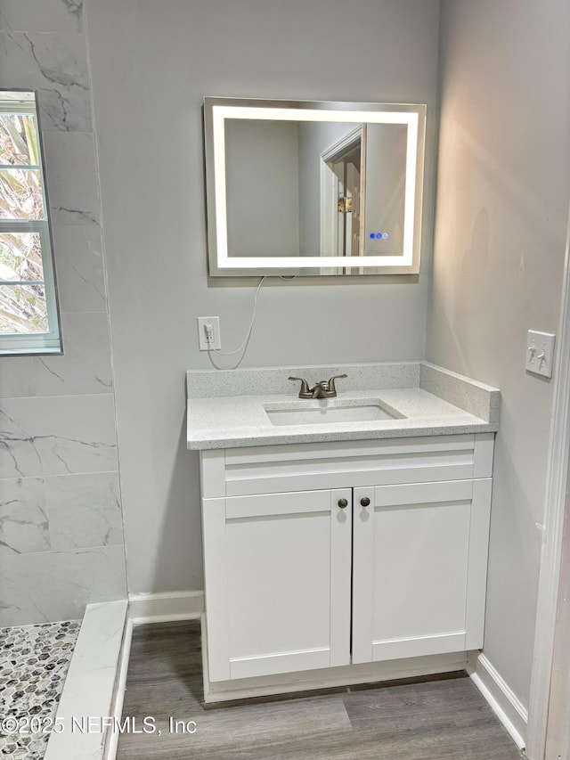 bathroom with vanity, wood-type flooring, and tiled shower