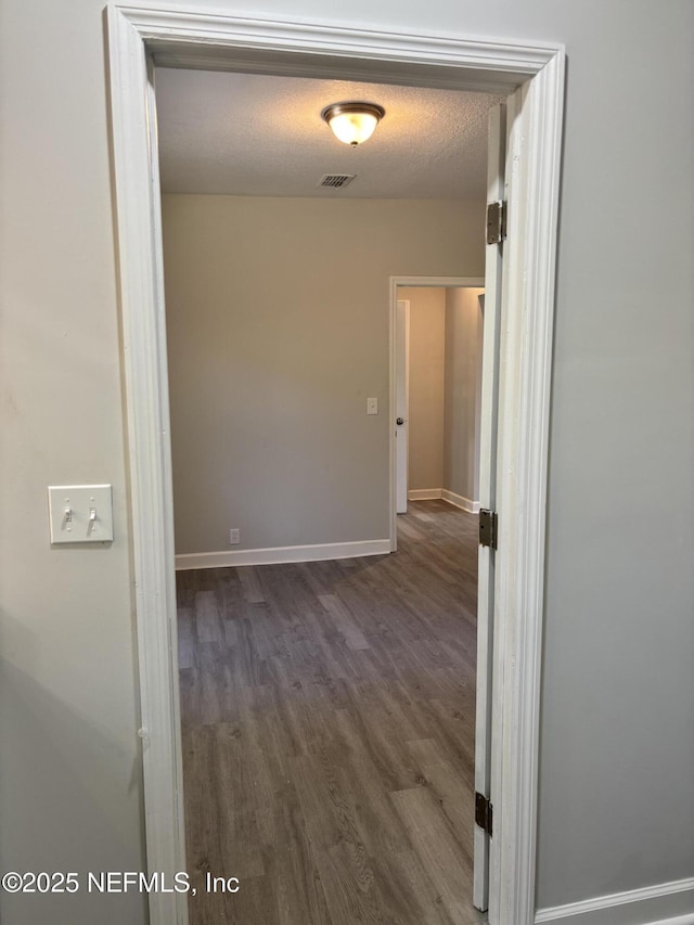 hallway with dark hardwood / wood-style floors and a textured ceiling