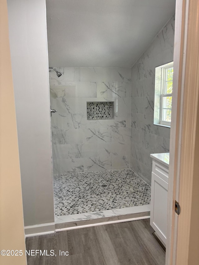 bathroom with hardwood / wood-style flooring, vanity, and tiled shower