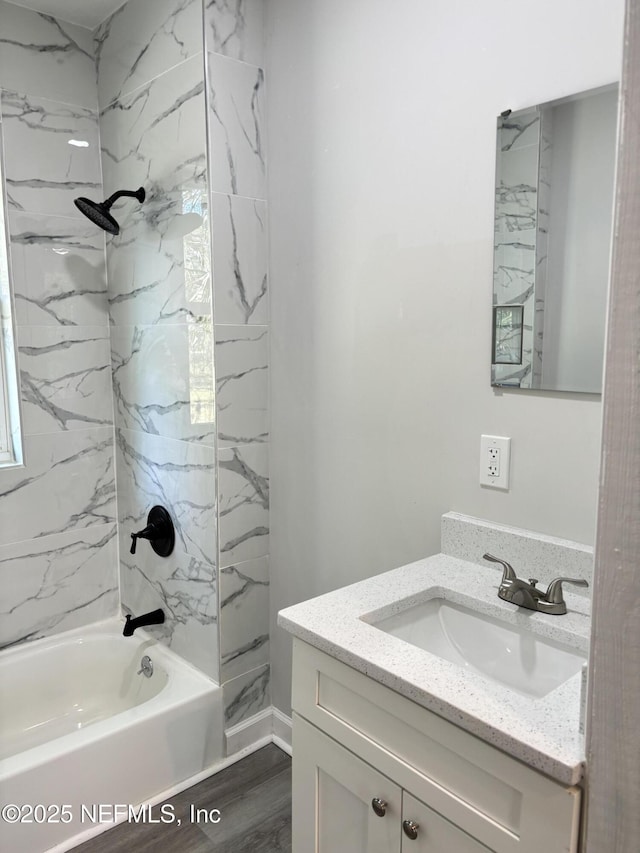 bathroom with tiled shower / bath combo, vanity, and wood-type flooring