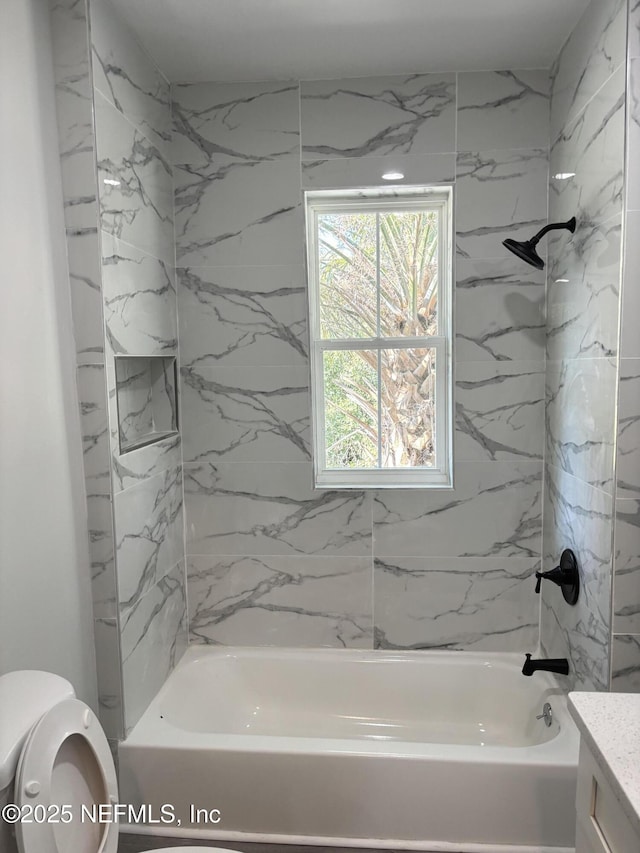 full bathroom featuring tiled shower / bath combo, vanity, and toilet