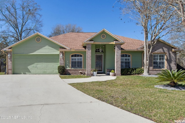 view of front of house with brick siding, a shingled roof, a front yard, a garage, and driveway