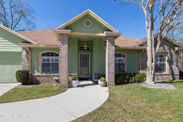 view of front of house with brick siding, an attached garage, a shingled roof, and a front yard