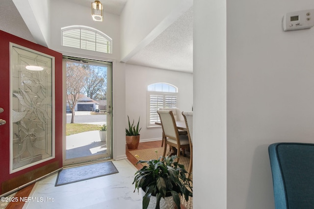 entrance foyer with baseboards, a textured ceiling, and marble finish floor