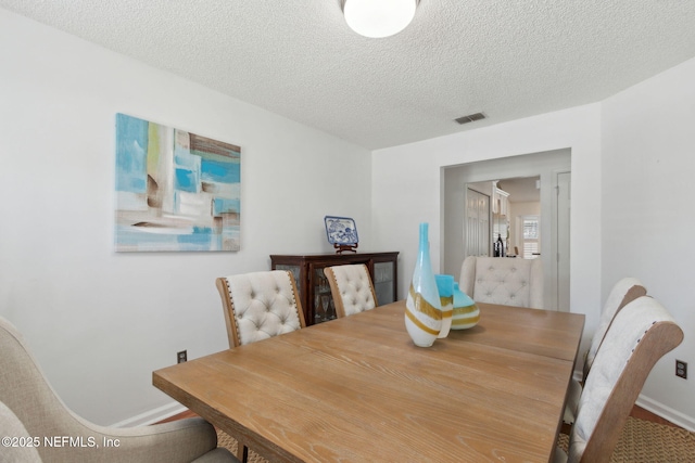 dining space with visible vents, baseboards, and a textured ceiling