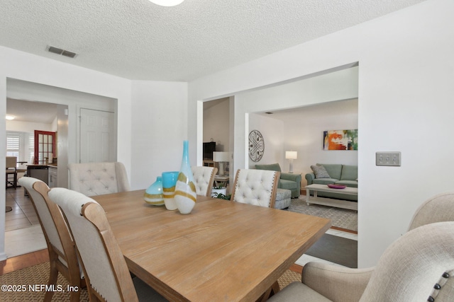 dining room with wood finished floors, visible vents, and a textured ceiling