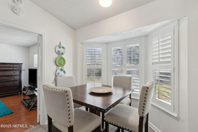 dining area featuring wood finished floors, baseboards, and a textured ceiling