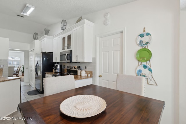 dining area featuring light tile patterned floors, visible vents, and a textured ceiling