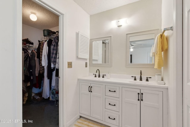 full bathroom featuring double vanity, a spacious closet, a textured ceiling, and a sink