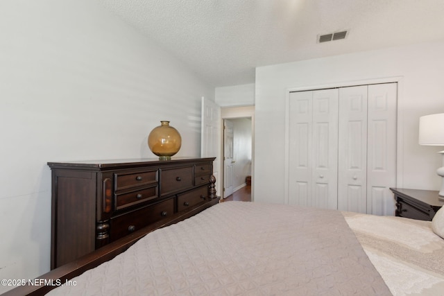 bedroom featuring visible vents, a textured ceiling, and a closet