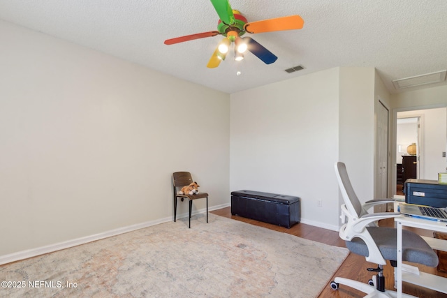 office area featuring visible vents, baseboards, ceiling fan, wood finished floors, and a textured ceiling