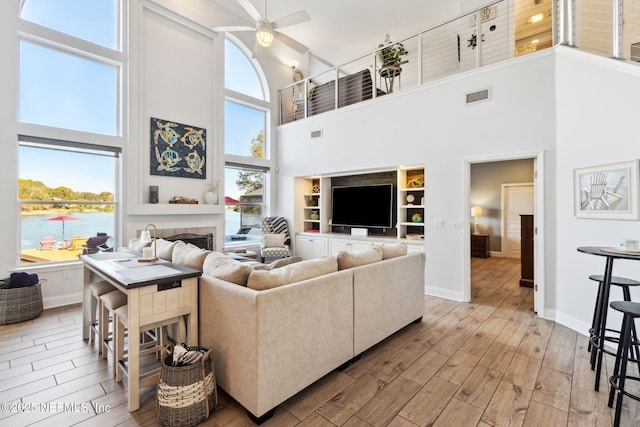 living room featuring a water view, a towering ceiling, and built in features