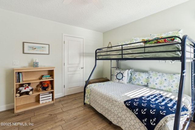 bedroom with hardwood / wood-style floors, a textured ceiling, and ceiling fan