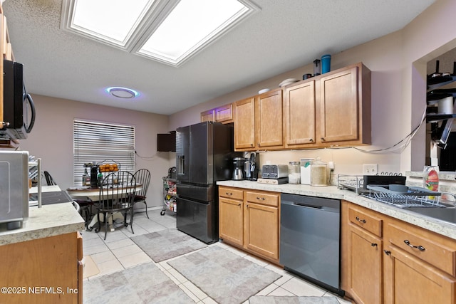 kitchen with light tile patterned floors, a skylight, black appliances, and a textured ceiling