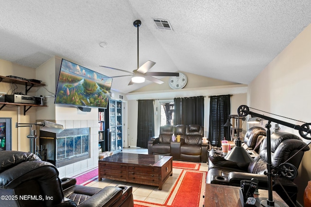 tiled living room featuring ceiling fan, a fireplace, vaulted ceiling, and a textured ceiling