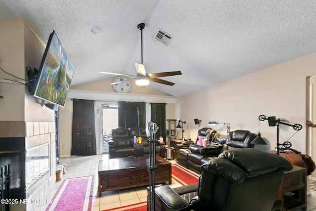 tiled living room featuring a tiled fireplace, a textured ceiling, vaulted ceiling, and ceiling fan