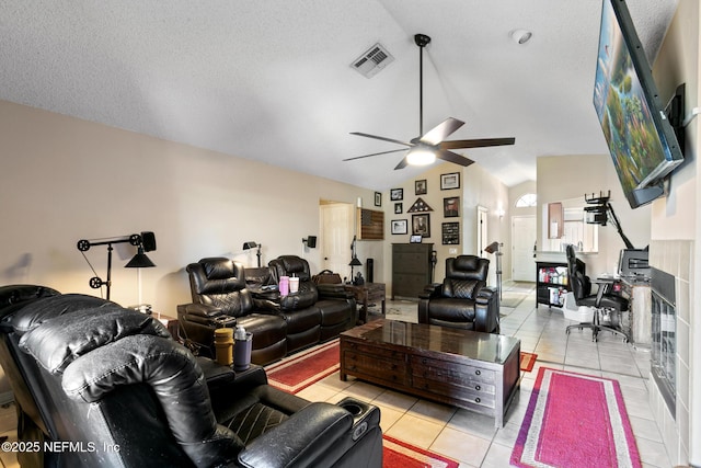 living room with ceiling fan, vaulted ceiling, a textured ceiling, and light tile patterned floors