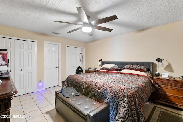 bedroom with light tile patterned floors, a textured ceiling, and multiple closets