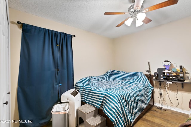 bedroom featuring ceiling fan, wood-type flooring, and a textured ceiling