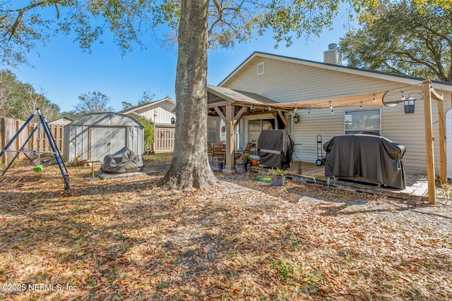 back of property with a playground and a shed