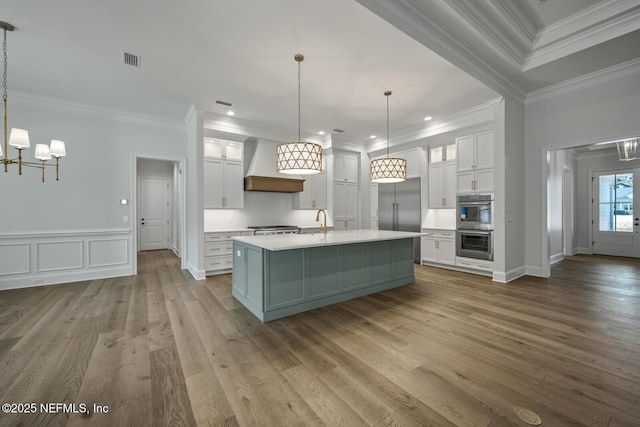 kitchen with hanging light fixtures, premium range hood, and white cabinets