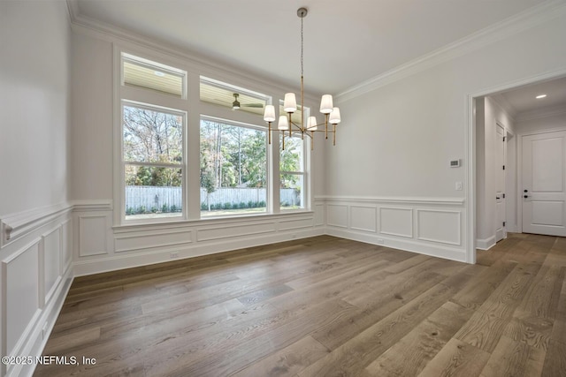 unfurnished dining area with crown molding, hardwood / wood-style flooring, and a chandelier