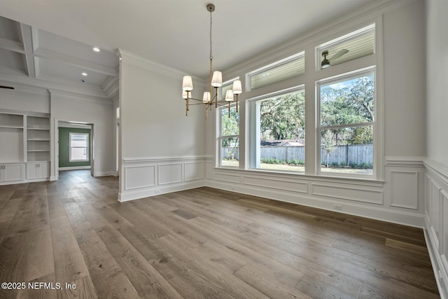 unfurnished dining area with coffered ceiling, beamed ceiling, crown molding, a notable chandelier, and hardwood / wood-style flooring