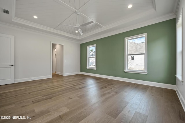 empty room featuring a raised ceiling, ornamental molding, and hardwood / wood-style floors