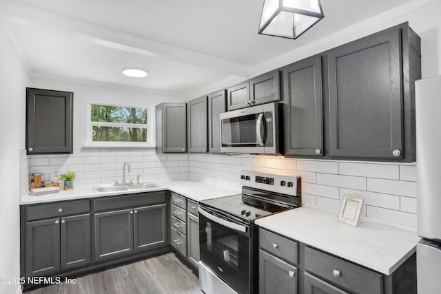 kitchen with sink, dark wood-type flooring, appliances with stainless steel finishes, gray cabinetry, and tasteful backsplash