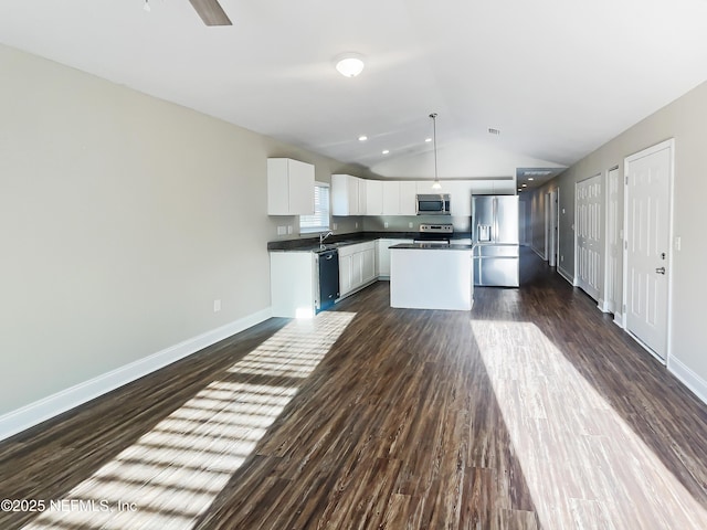 kitchen featuring appliances with stainless steel finishes, white cabinets, hanging light fixtures, a center island, and dark wood-type flooring