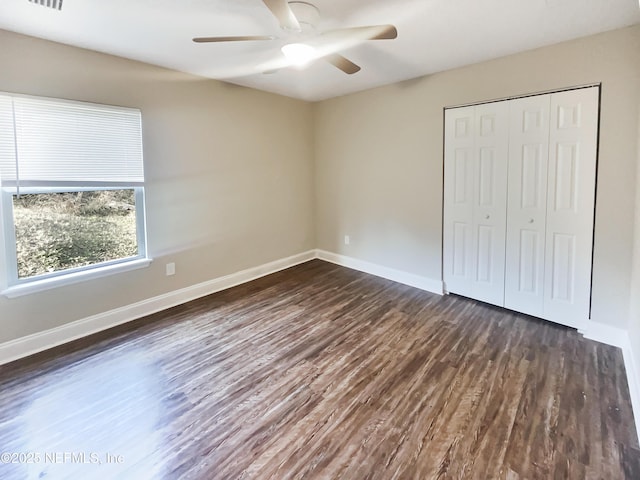 unfurnished bedroom with dark wood-type flooring, ceiling fan, and a closet