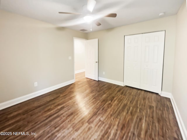 unfurnished bedroom with dark hardwood / wood-style floors, a closet, and ceiling fan