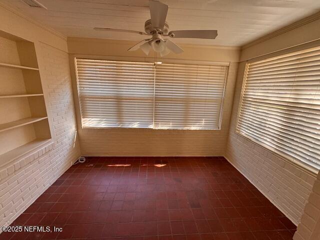 unfurnished sunroom featuring ceiling fan and a healthy amount of sunlight