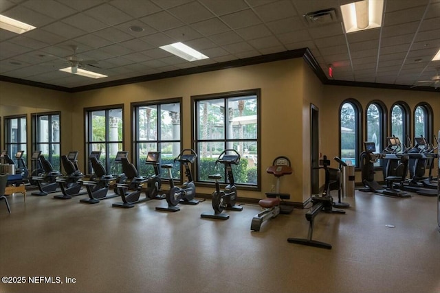 workout area with ceiling fan, a paneled ceiling, and ornamental molding